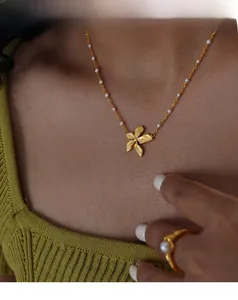 Dettaglio della collana con ciondolo a fiore d'oro con perline bianche e anello