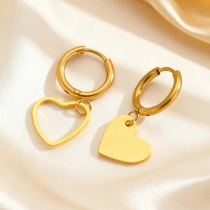 Detail von zweifarbigen Gold-Creolen mit asymmetrischen hohlen und massiven Herzanhängern