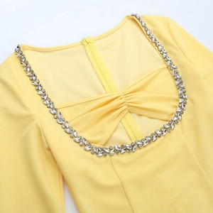 Détail d'une robe jaune à col carré ornée de strass argentés scintillants et élégants