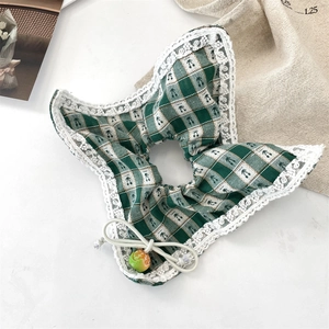 Detail of green plaid scrunchie featuring white lace edges and a fruit-shaped pendant