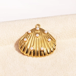 Macro shot of gold shell pendant with pearl inlay on beige textured fabric background