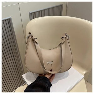 Detail of beige crescent bag with silver metallic bow and adjustable strap