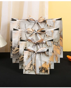 Set of four grey marble pattern gift bags with gold accents and elegant ribbon bows