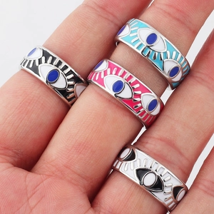 Close-up of four gold-plated evil eye rings with colorful enamel on hand for detailed look