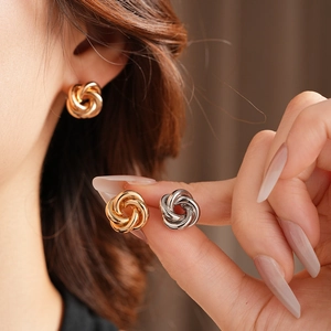 Close-up of model wearing gold and silver twisted metal stud earrings with high-end texture
