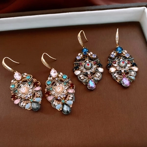 Macro detail of vintage zircon drop earrings with intricate crystal inlay and gold hooks