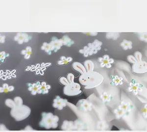 Macro detail of 5D nail art stickers featuring white bunnies and daisy flower patterns