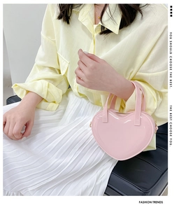 Detail of pink heart-shaped patent leather handbag with metallic zipper and side hooks