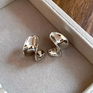 Macro detail of silver-colored liquid metal C-shape earrings in a velvet jewelry box