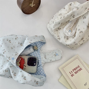 Close-up of floral canvas wristlet bag with lace trim and inner checkered lining details