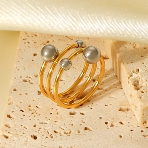 Detail shot of multi-layer gold spiral ring with silver spheres on beige stone