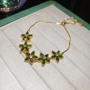Detail of adjustable gold flower bracelet with green and white cubic zirconia crystals