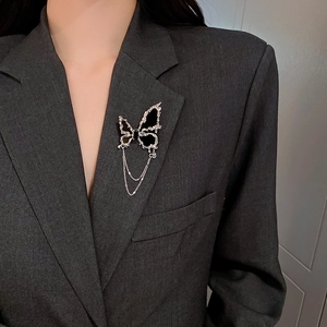 Détail d'une broche papillon noire avec pampilles argentées sur un revers de veste