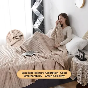 Beige cotton waffle weave blanket for bed or sofa in a cozy home setting
