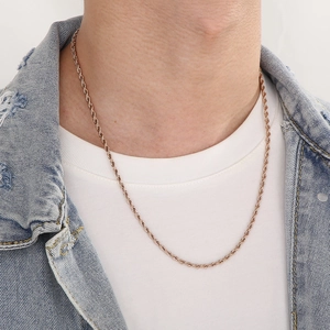 Detail of rose gold rope chain necklace worn with denim jacket showing twisted texture
