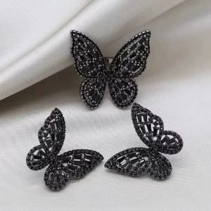 Detail of elegant black butterfly jewelry set with sparkling stones on beige silk