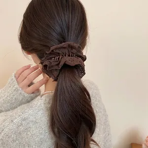 Dark brown double-layered eyelet lace scrunchie with embroidery shown on a ponytail