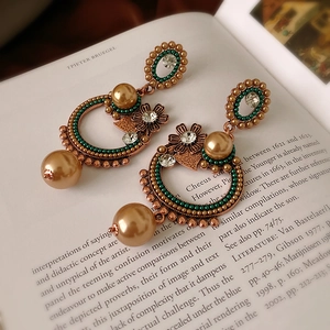 Détail de boucles d'oreilles vintage avec perles et perles vertes sur un livre