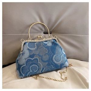 Macro detail of denim kiss-lock bag with cloud print, gold hardware, and diamond clasp