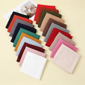 Over twenty solid colors of soft cotton linen scarves arranged neatly on a beige background