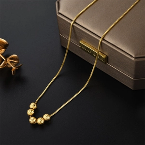 Vintage gold beaded pendant necklace on black background with elegant studio lighting