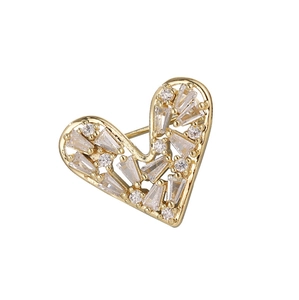 Close-up of heart-shaped gold brooch with inlaid sparkling clear zircons and polished finish
