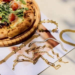 Flat lay of multiple gold stainless steel zircon bracelets on a white minimalist background