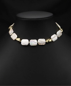 Close-up of white baroque rectangle pearls and gold irregular metal beads on a necklace