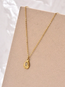Detailed close-up of a teardrop-shaped white zircon pendant on a gold necklace chain