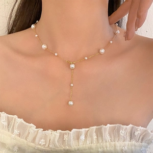 Elegant gold Y-shaped titanium necklace with white pearls on a model neck