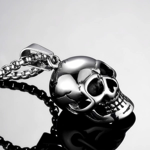 Detailed macro shot of a polished silver skull pendant on a heavy metal chain