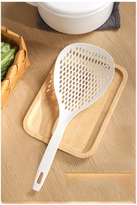 Close-up of a large white nylon slotted spoon with ergonomic long handle on wooden tray