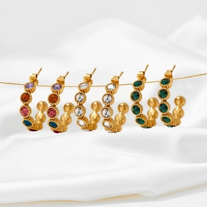 Vintage C-shaped gold-plated stud earrings with colorful crystals on white silk background