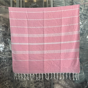Detail of pink and white striped Turkish beach towel with handmade white tassel fringe