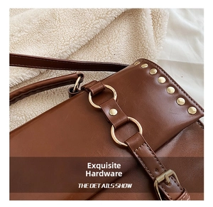 Detail of vintage brown leather bag with golden rivets and interlocked ring hardware