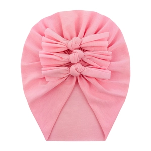 Close-up of pink soft cotton baby hat featuring a stylish triple bow detail on white background