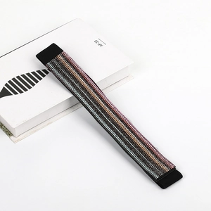 Detail shot of black elastic belt with rows of multi-color rhinestones on white prop
