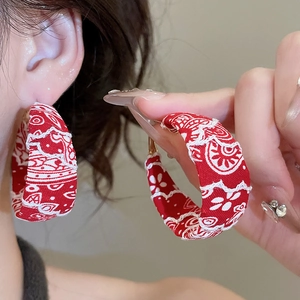 Gros plan sur les créoles en tissu rouge avec imprimés ethniques et motifs de fleurs