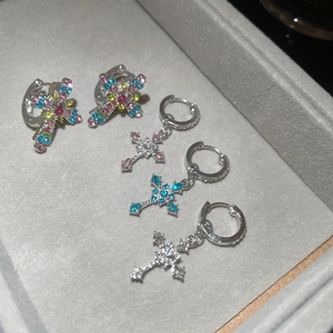 Detail view of colorful zircon cross drop earrings set in a grey velvet jewelry box