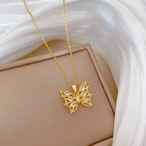 Détail macro du pendentif papillon doré avec zircons marquise sur fond de satin blanc