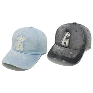 Close-up of vintage washed denim baseball caps with H patch embroidery and distressed holes