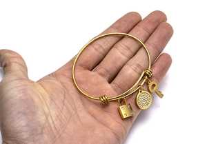 Close-up of gold adjustable wire bracelet with crystal encrusted lock and key charms
