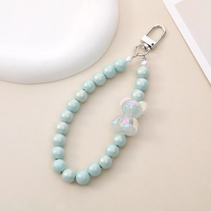 Detail of light blue pearl beads and iridescent bear pendant on a silver keychain