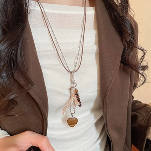 Detail of vintage layered necklace with tiger eye heart pendant and coral-style branch