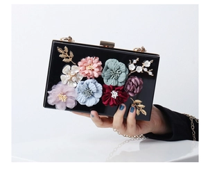 Detail of black acrylic evening clutch with 3D colorful floral accents and gold chain