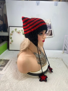 Detail of hand-knitted cat ear hat with striped pattern and star-shaped charms