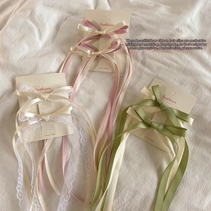 Close-up of ballet-style bow hair clips with long tassels in pink, white, and green