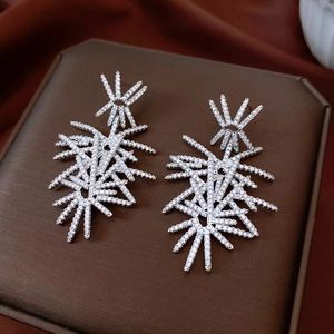 Macro shot of silver fireworks pendant earrings with micro-pave zircons on brown leather