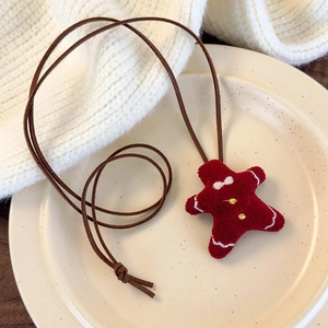 Close-up of a gingerbread man plush pendant on a ceramic plate for Christmas decor