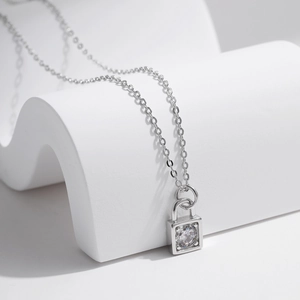 Silver lock pendant necklace with a brilliant round moissanite on a minimalist background